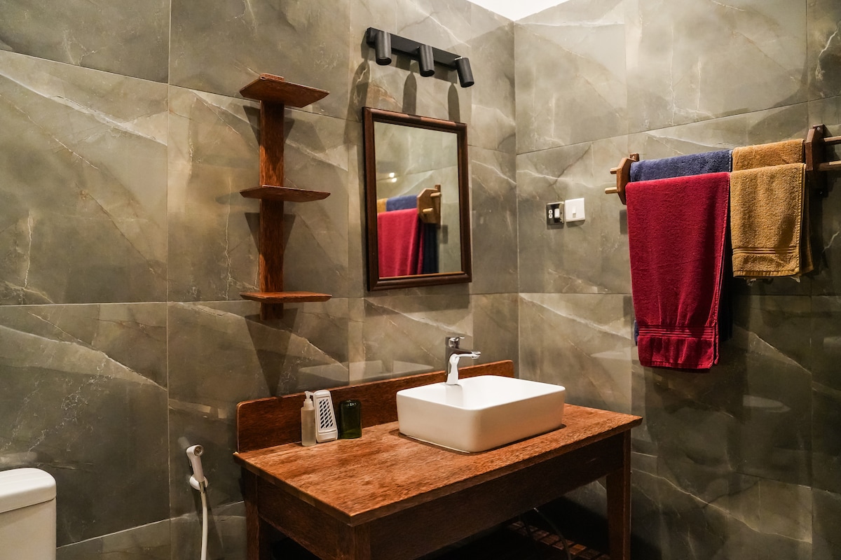 En-suite bathroom with dark marble tiles and wooden vanity